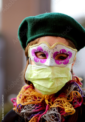 little girl with health mask and carnival mask for protection against the Virus crown photo