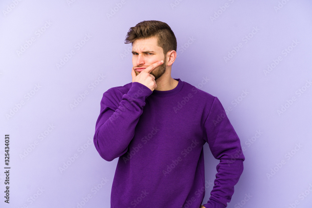 Fototapeta premium Young caucasian man isolated on purple background contemplating, planning a strategy, thinking about the way of a business.