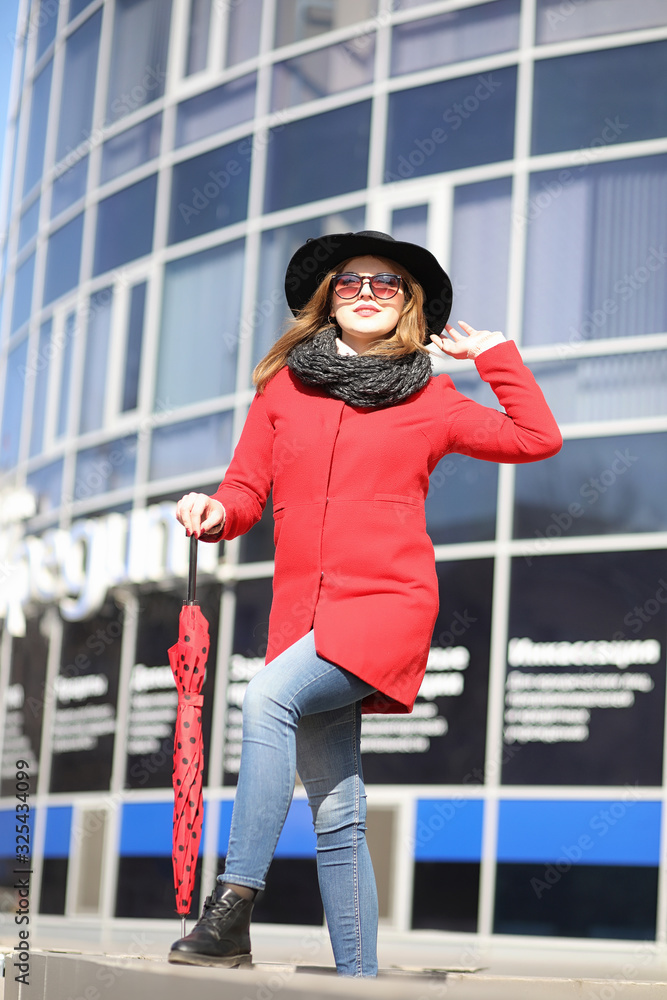 Obraz premium Pretty girl on a walk in red coat in the city