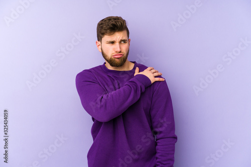 Young caucasian man isolated on purple background having a shoulder pain. © Asier