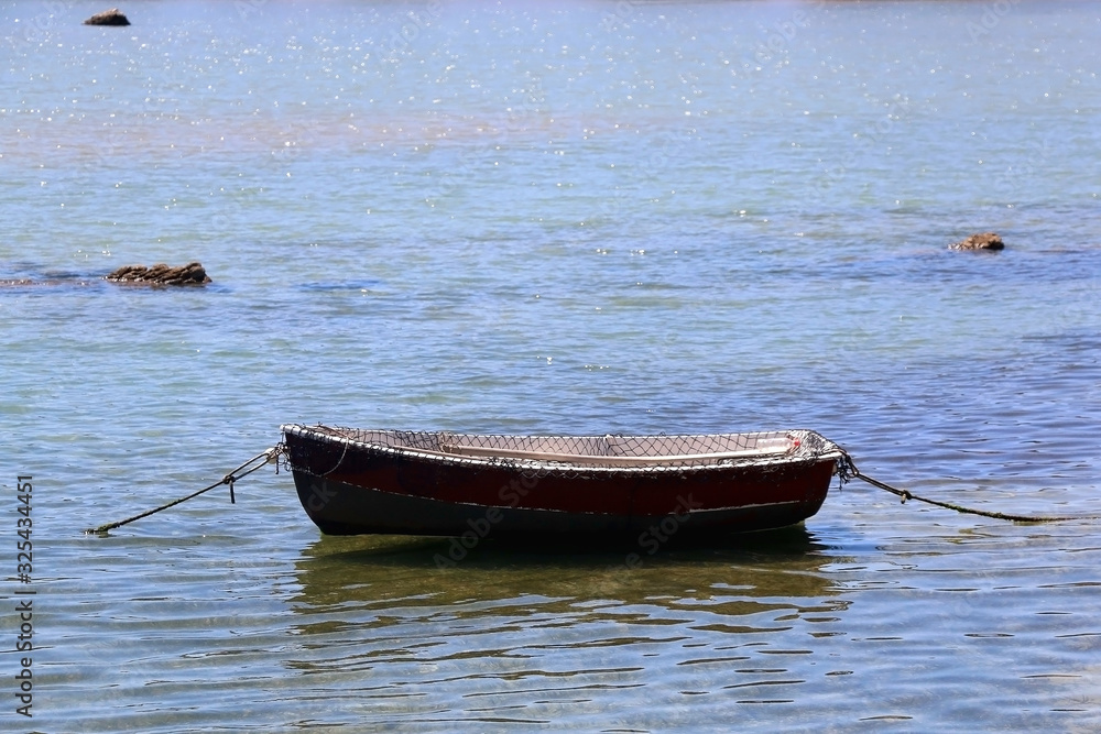 Small rustic fishing boat in a shallow sea. Selective focus.