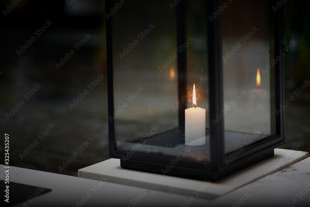 Candle in glass housing on floor in dark time with flame Candle in glass housing on floor in dark time with flame