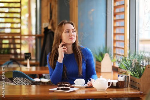 Young girl in cafe sits and drinks tea