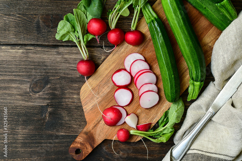 radishes and zucchini sliced on a wooden board. salad with fresh seasonal vegetables. diet food. vegan recipe healthy food