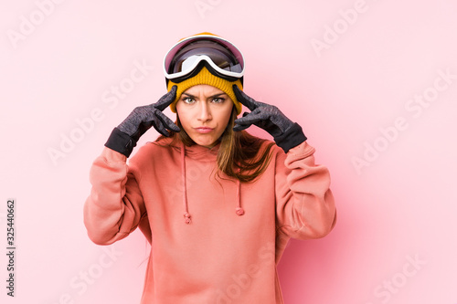 Young caucasian woman wearing a ski clothes isolated focused on a task, keeping forefingers pointing head.