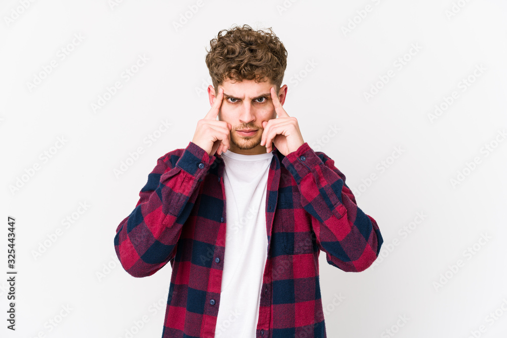 Young blond curly hair caucasian man isolated focused on a task, keeping forefingers pointing head. Young blond curly hair caucasian man isolated focused on a task, keeping forefingers pointing head.