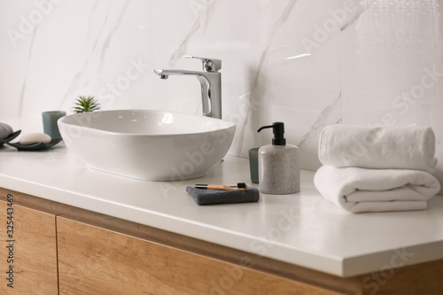 Toiletries and stylish vessel sink on light countertop in modern bathroom
