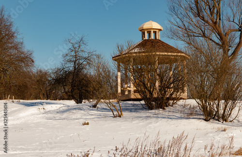 Manor Grebnevo winter gazebo on Bank of Barsky pond at bright Sunny day on natural background