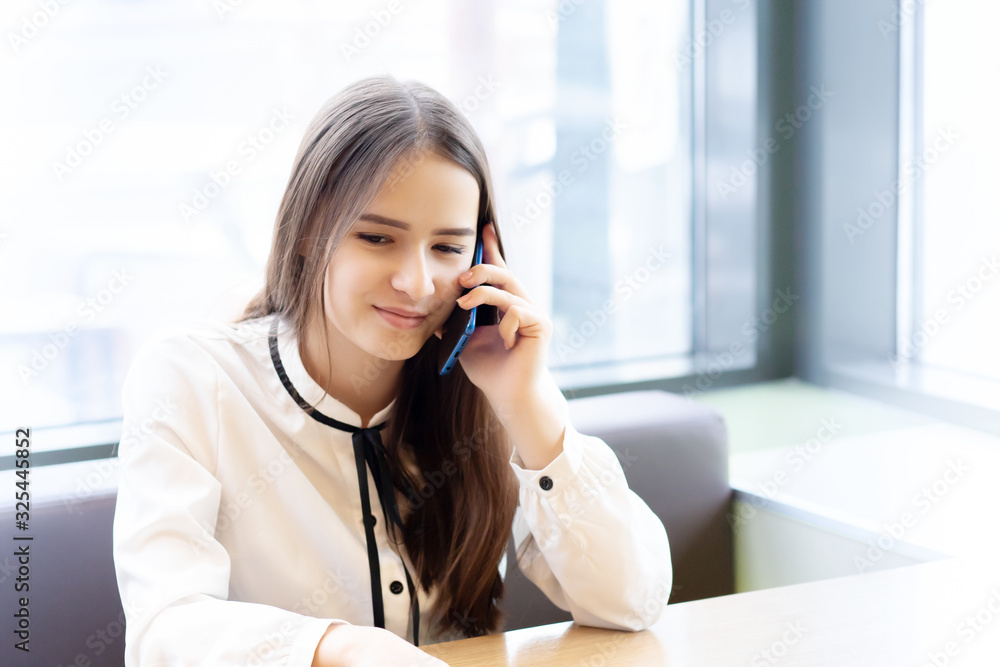 Young woman office worker in a cafe with a smartphone, talking, smiling Young woman office worker in a cafe with a smartphone, talking, smiling