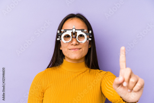 Youn indian woman with optometry glasses showing number one with finger.