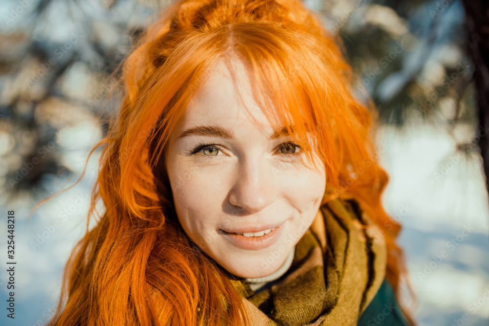 Portraits of a charming red-haired girl with a cute face. Girl posing on camera in the city center in winter. She has a wonderful mood and a lovely smile Portraits of a charming red-haired girl with a cute face. Girl posing on camera in the city center in winter. She has a wonderful mood and a lovely smile