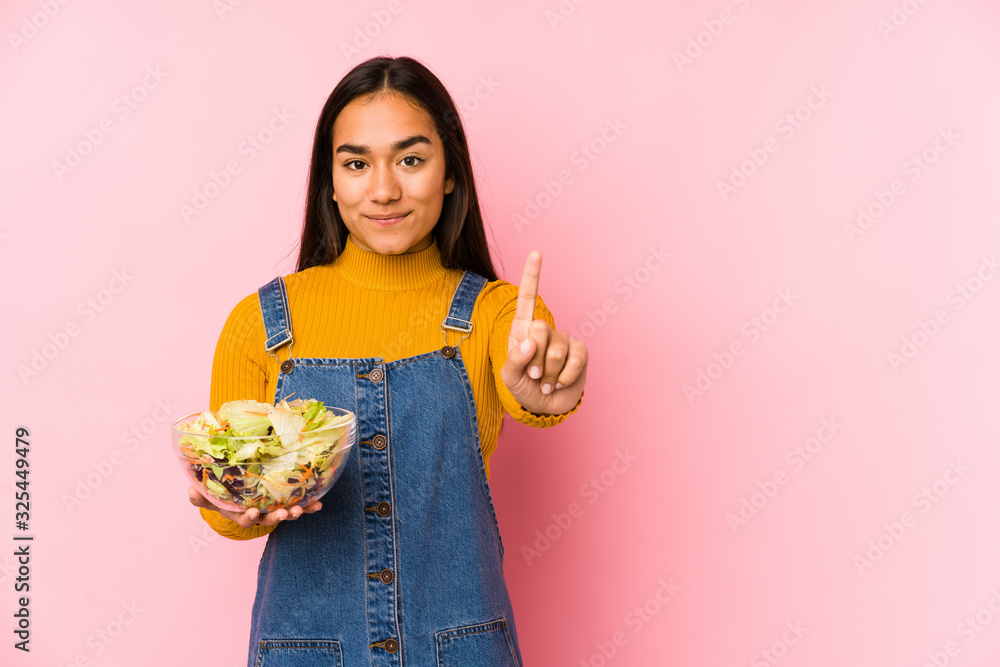 Young asian woman holding a salad isolated showing number one with finger. Young asian woman holding a salad isolated showing number one with finger.