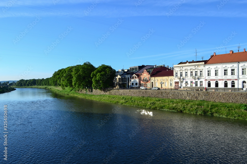 Fototapeta premium river and embankment, blue sky, white clouds, linden trees, Uzhhorod, Ukraine