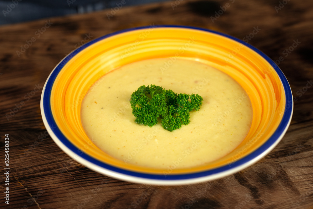 Cauliflower, Potato and cheese cream soup served in plate on wooden table Cauliflower, Potato and cheese cream soup served in plate on wooden table