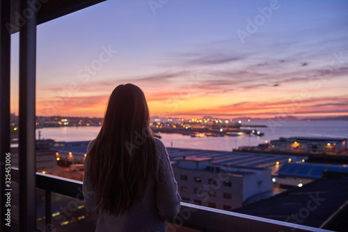 Young woman contemplating the sea from a balcony