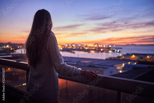Young woman contemplating the sea from a balcony