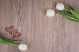 Wooden background with white tulips and red hearts and free space for text