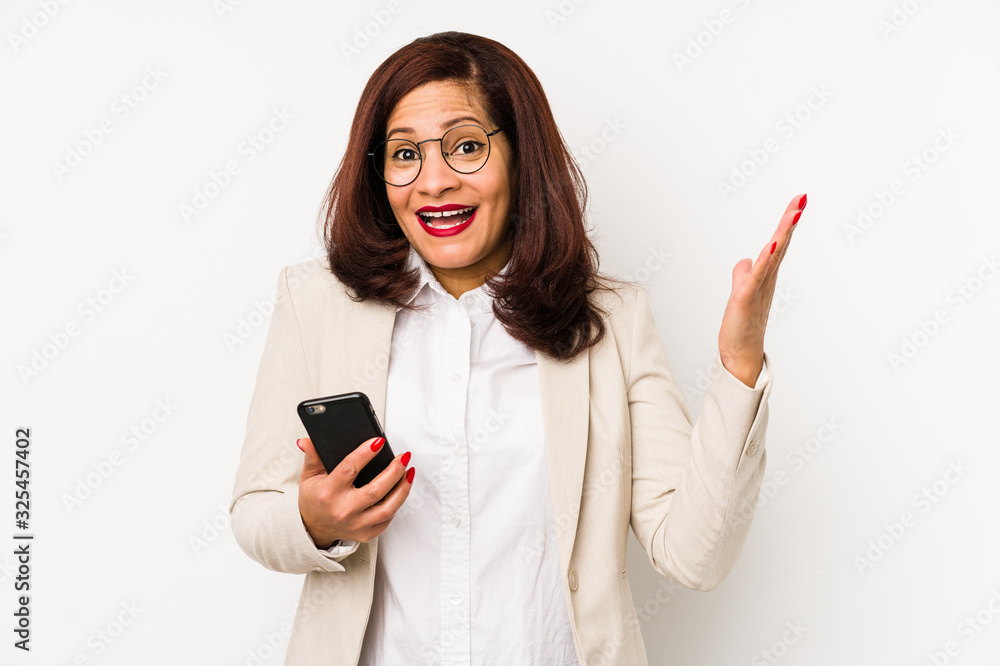 Middle age latin woman holding a mobile phone isolated receiving a pleasant surprise, excited and raising hands. Middle age latin woman holding a mobile phone isolated receiving a pleasant surprise, excited and raising hands.