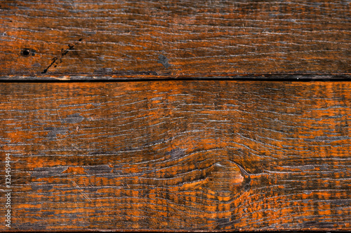 Texture of old wooden board that have been processed into furniture with a bright reddish orange varnish coating. Vintage cracked wood surface background with natural lines.
