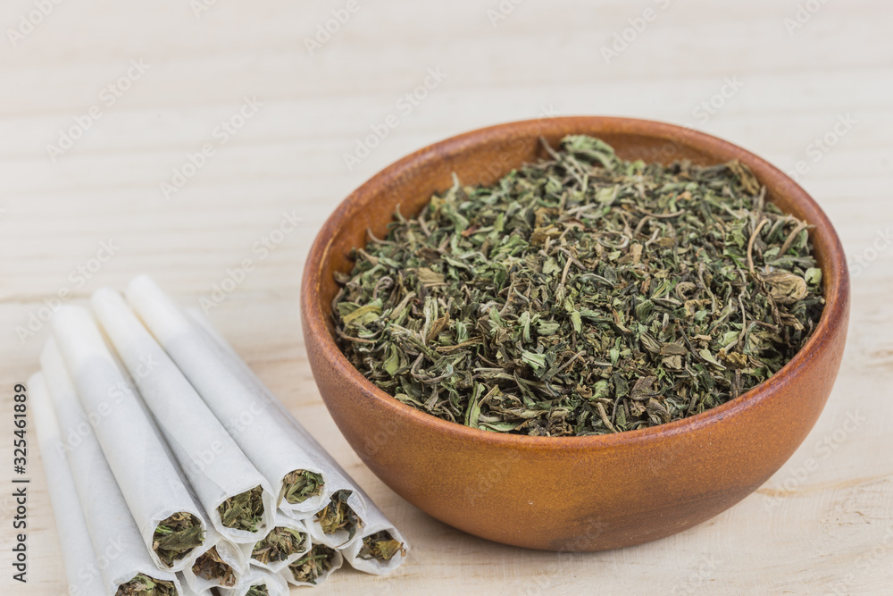 Marijuana or weed or cannabis on wooden bowl and in the rolled joint. Marijuana or weed or cannabis on wooden bowl and in the rolled joint.