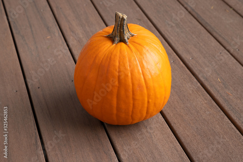 Cute round pumpkin sitting on a wood deck