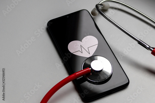 Schwarzes Smartphone mit Herzsymbol und Herzschlag und Stethoskop zeigen digitale Patientenakte, digitale Gesundheitsprogramme und Fitnesstracker in der modernen Gesundheitspraxis photo