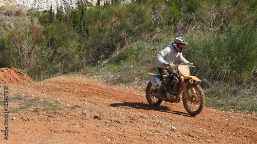 Zoom photo of unidentified motocross rider performing extreme stunts in off road dirt track