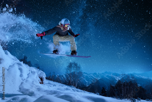 night skating girl is jumping with snowboard under the starry sky and moonlight