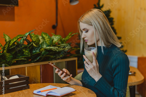 beautiful blrndinka woman in business casual style while working in a cafe and restaurant coffee.lifestyle woman on the phone drinking coffee text message on smartphone app.attractive girl with a note