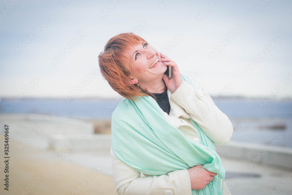 Beautiful girl in autumn weather talks on the phone, smiles and rejoices Beautiful girl in autumn weather talks on the phone, smiles and rejoices