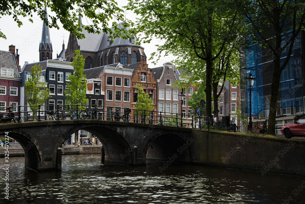 Cityscape of Amsterdam. Dutch city architecture. Modern exterior of buildings. An elegant bridge over the canal.
