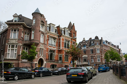 Fototapeta Naklejka Na Ścianę i Meble -  Cityscape of Amsterdam. Dutch city architecture. Modern exterior of buildings. Parking cars.