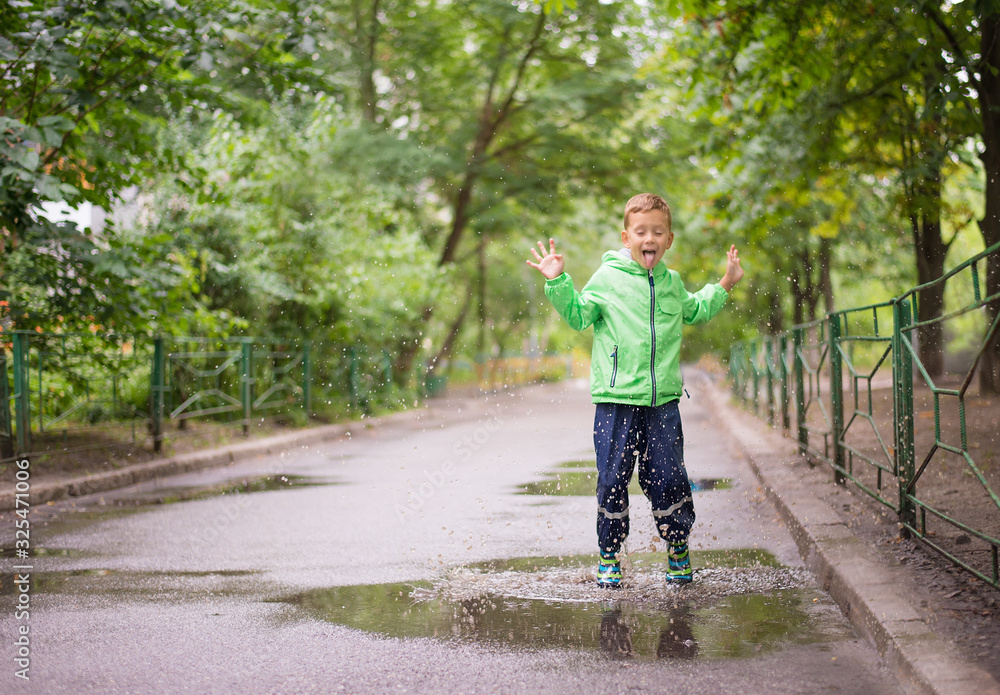 cheerful boy jumping puddles with big splash cheerful boy jumping puddles with big splash