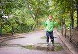 cheerful boy jumping puddles with big splash