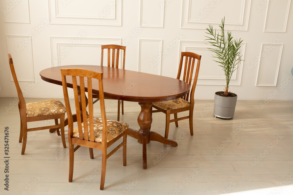 A classic set of wooden furniture for the kitchen. A set of chairs to the table in a classic interior