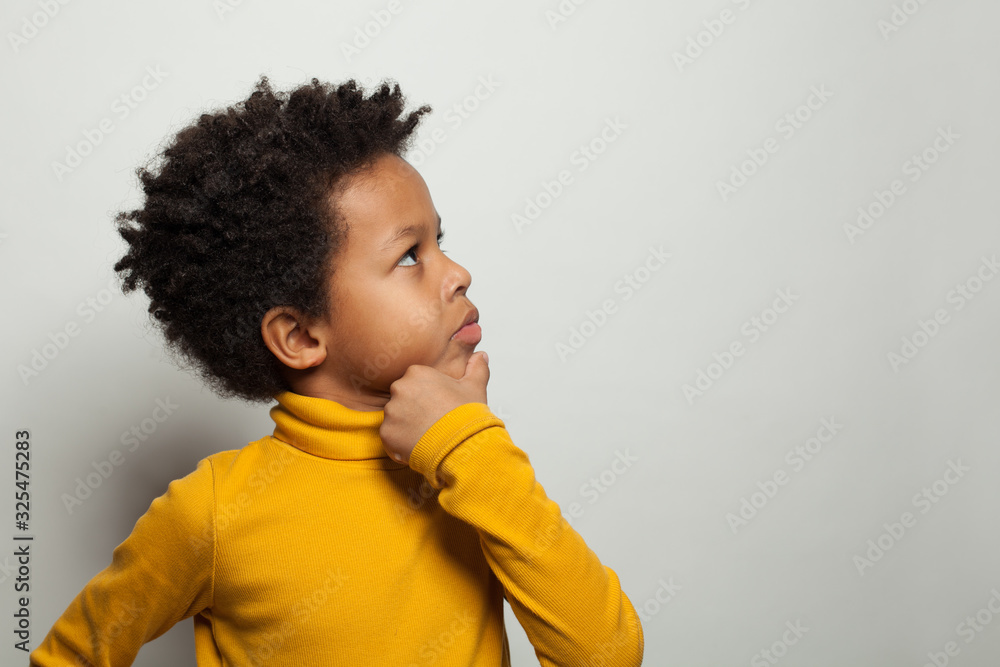 Small black kid boy thinking and looking up on white background Stock