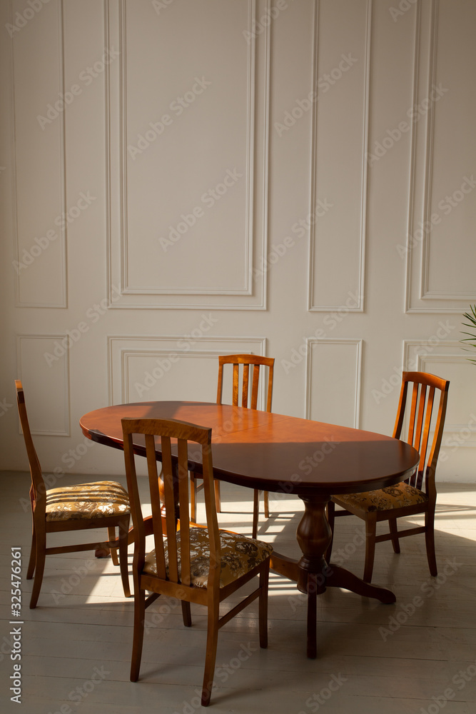 A classic set of wooden furniture for the kitchen. A set of chairs to the table in a classic interior