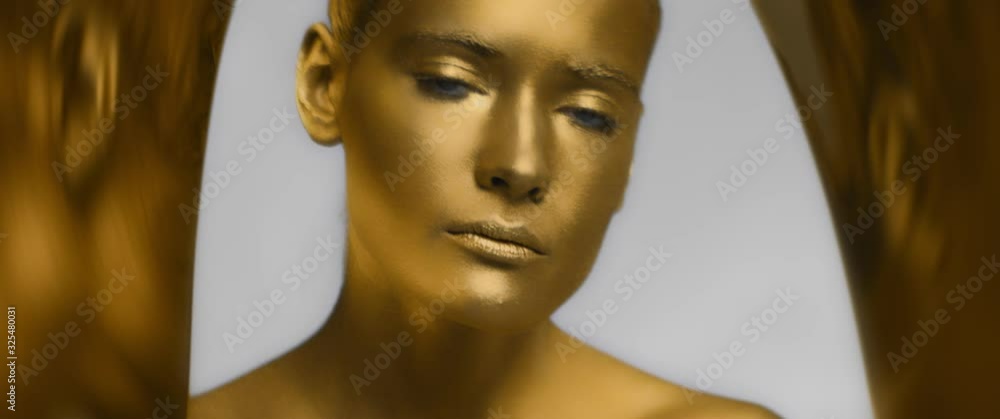 female model with gold trendy makeup and body art open her eyes and looks at camera, fashion trend, blue eyes, bronze or golden skin color or tone, reflective surface, anamorphic shot female model with gold trendy makeup and body art open her eyes and looks at camera, fashion trend, blue eyes, bronze or golden skin color or tone, reflective surface, anamorphic shot