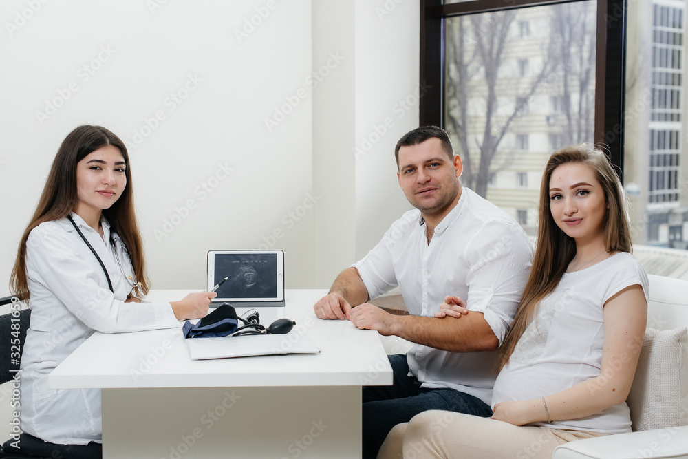 A young couple waiting for a baby to consult a gynecologist after an ultrasound. Pregnancy, and health care A young couple waiting for a baby to consult a gynecologist after an ultrasound. Pregnancy, and health care