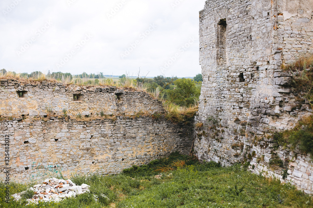 Old ruins of Skala Podilskyi castle, Ukraine. Destroyed ruined stone walls of medieval castle and green grass, historical defence fortress in Europe