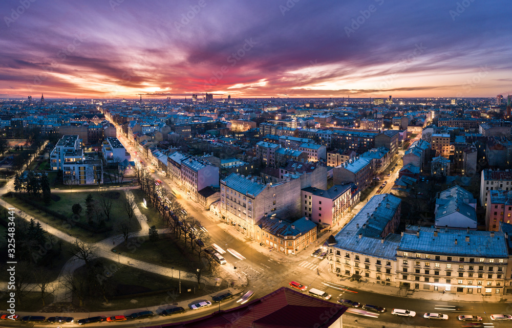 Obraz premium Aerial view of busy city in colorful sunset and street lights. Drone shot of Riga city. 