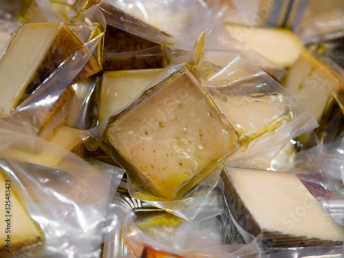 Various pieces of cheese in olive oil in plastic bags at a market stand