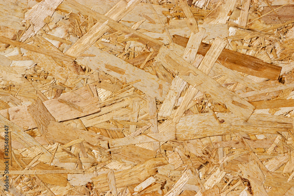 Pressed wood board texture: particle board. Production of natural materials for the construction of structures. Bright sunshine. Pressed wood board texture: particle board. Production of natural materials for the construction of structures. Bright sunshine.