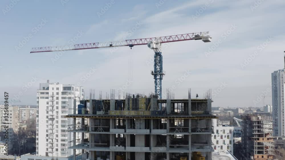 An approaching aerial shot from the side of a gray high-rise office building under construction. Lifting from a bird's eye view. The construction of new house for living, the city of Kharkov, Ukraine. An approaching aerial shot from the side of a gray high-rise office building under construction. Lifting from a bird's eye view. The construction of new house for living, the city of Kharkov, Ukraine.