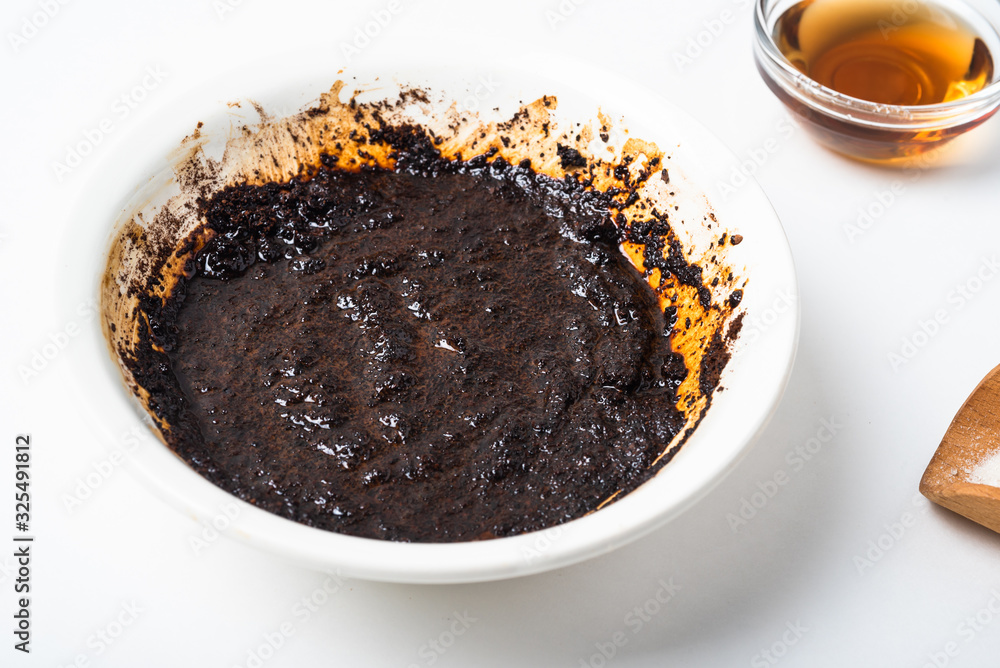 Homemade coffee body scrub made from coffee, sugar and butter in a bowl on a light background Homemade coffee body scrub made from coffee, sugar and butter in a bowl on a light background