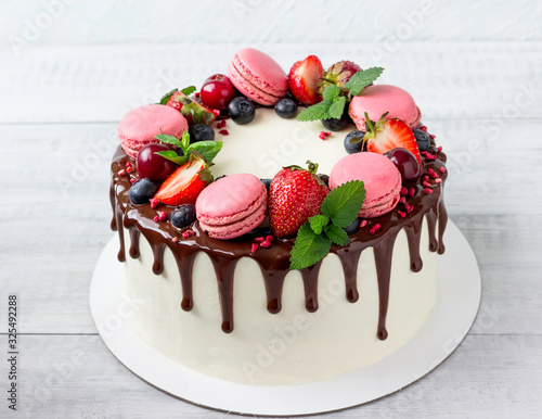 Birthday Drip Cake with chocolate ganache, fresh berries, macaroons and mint .