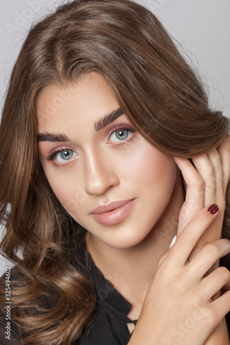 Portrait of a beautiful happy woman with long eyelashes, beautiful fresh nude make-up, thick eyebrows and with clean skin in a beauty salon. Eyelash extensions. Face close-up. Make-up concept