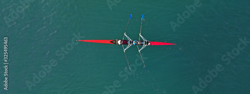 Aerial drone ultra wide photo of young athletes rowing in canoe competition in tropical lake with emerald waters
