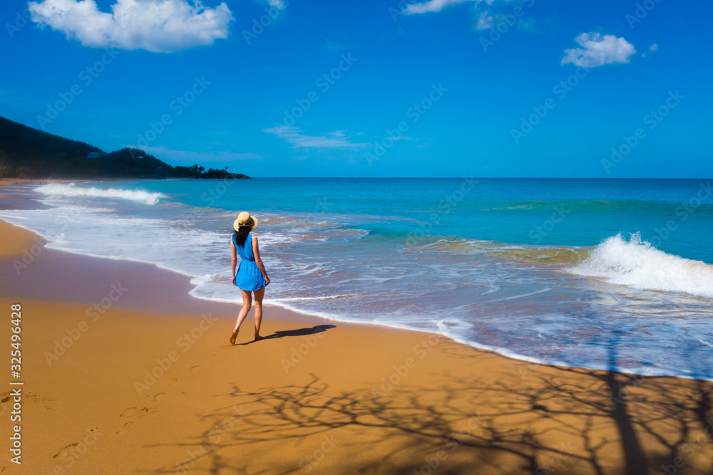 Girl in blue dress walking at Caribbean beach