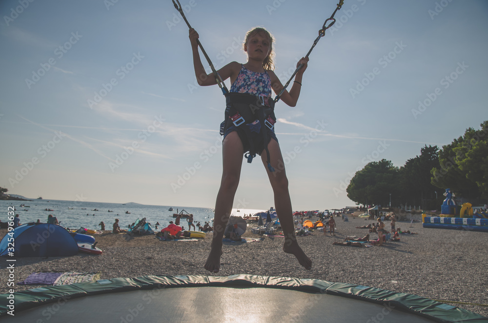 active child in bungee jumping trampoline at sunset